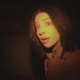 A woman looks at the camera in a dark scene from V/H/S/94.